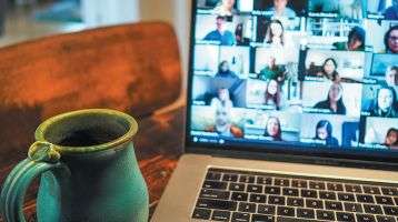 A desktop with an open laptop computer and coffee cup