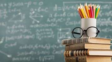Stack of books and pencils in front of a blackboard 